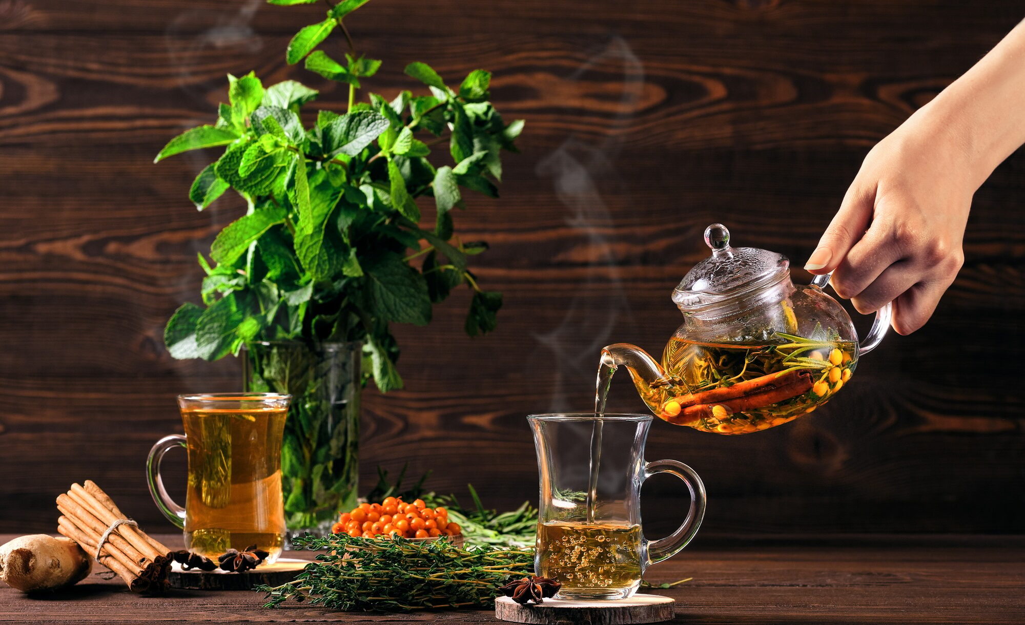 Pouring hot herbal tea with sea buckthorn