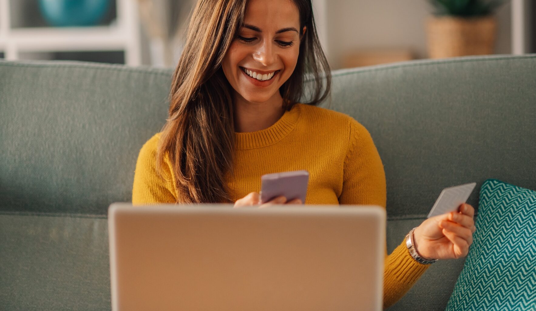 Woman buying online on a laptop at home and using a smartphone